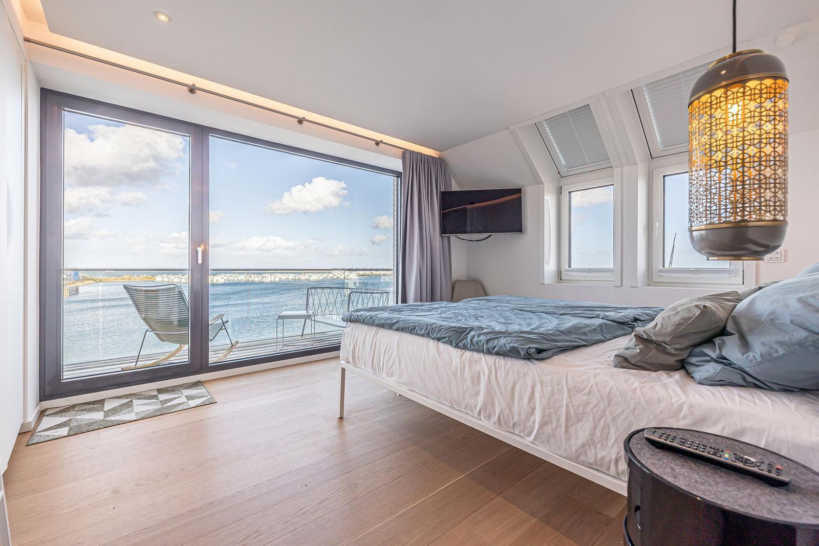 Schlafzimmer mit Blick aufs Wasser und Balkon mit Stuhl.