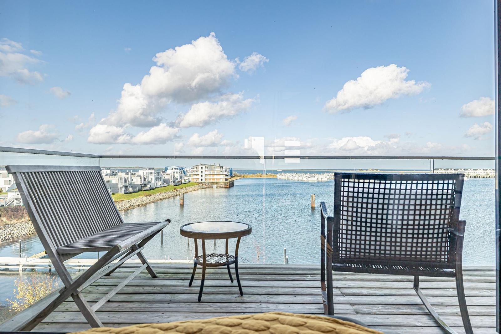 Terrasse mit Stühlen und Tisch bietet Blick auf Wasser und Häuser.