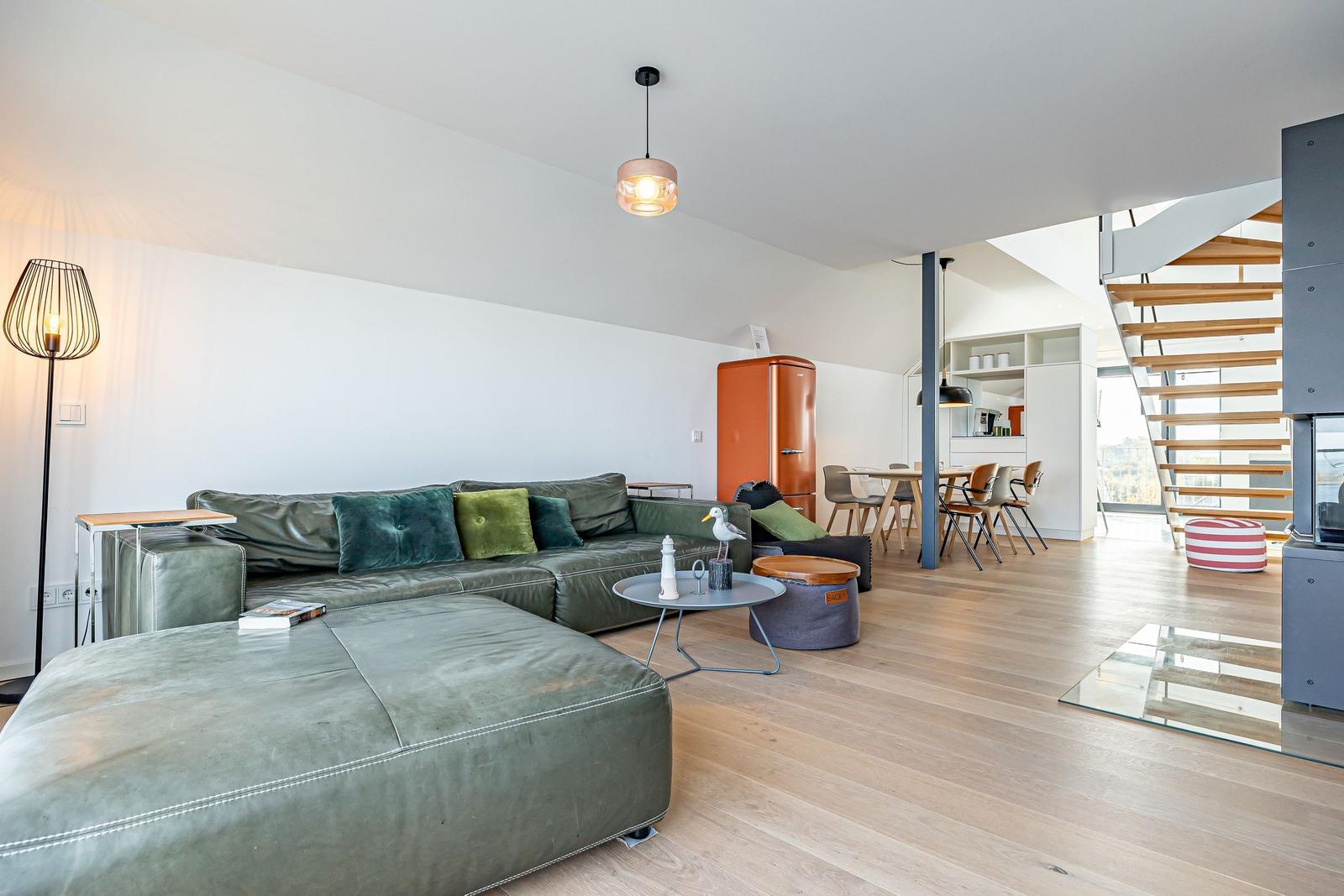 Wohnbereich mit grünem Sofa, Holzboden und moderner Einrichtung.