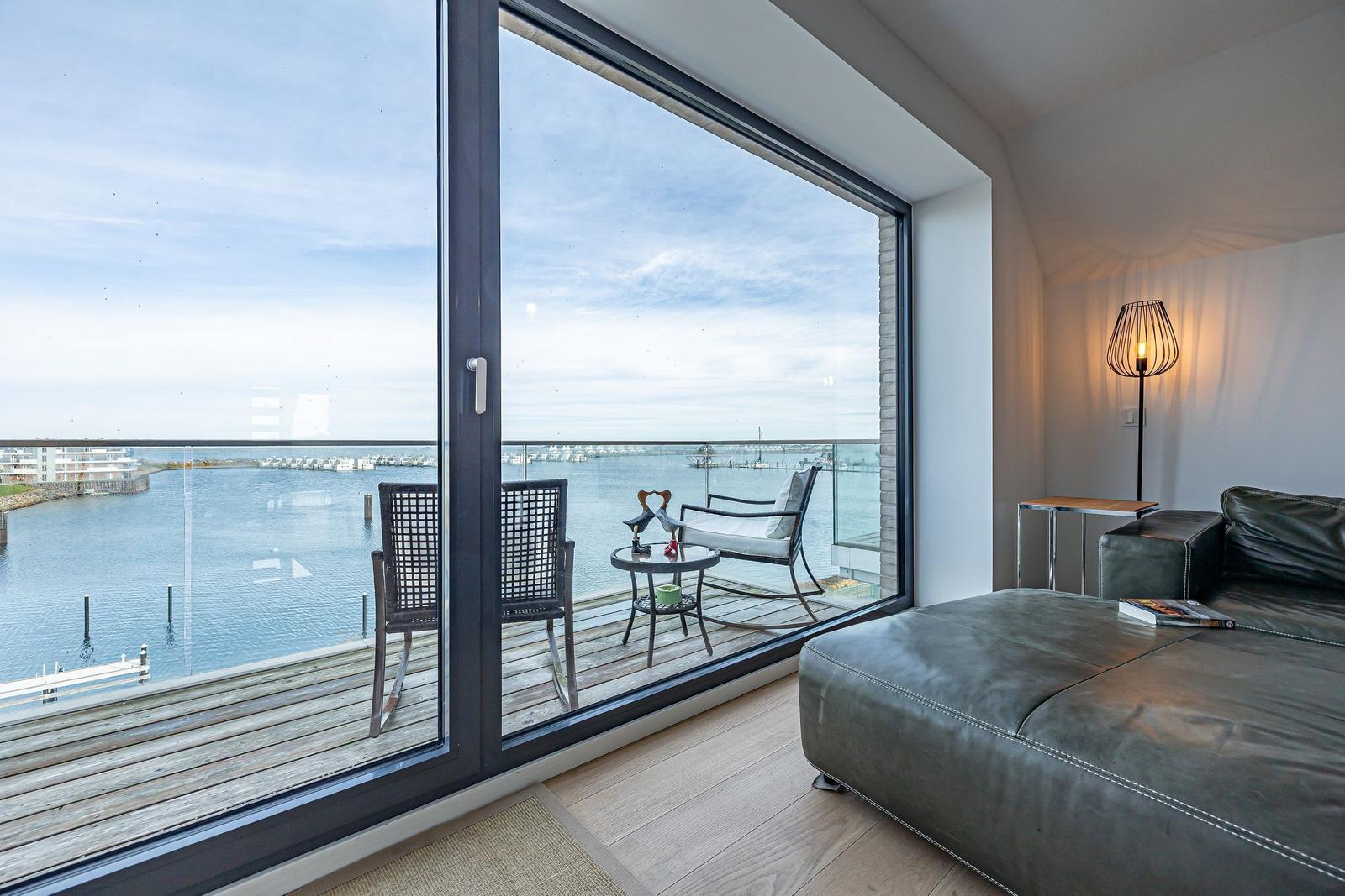 Wohnzimmer mit Balkonblick auf Hafen und Wasser.