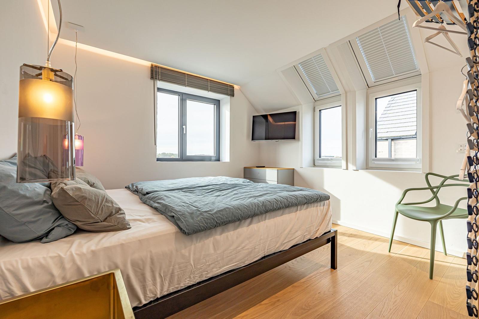 Schlafzimmer mit Dachschrägen, Bett, TV und Fenster.