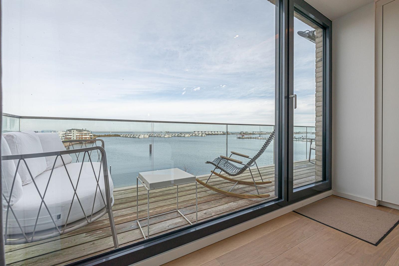Terrasse mit weißem Sofa und Schaukelstuhl über Wasserblick.