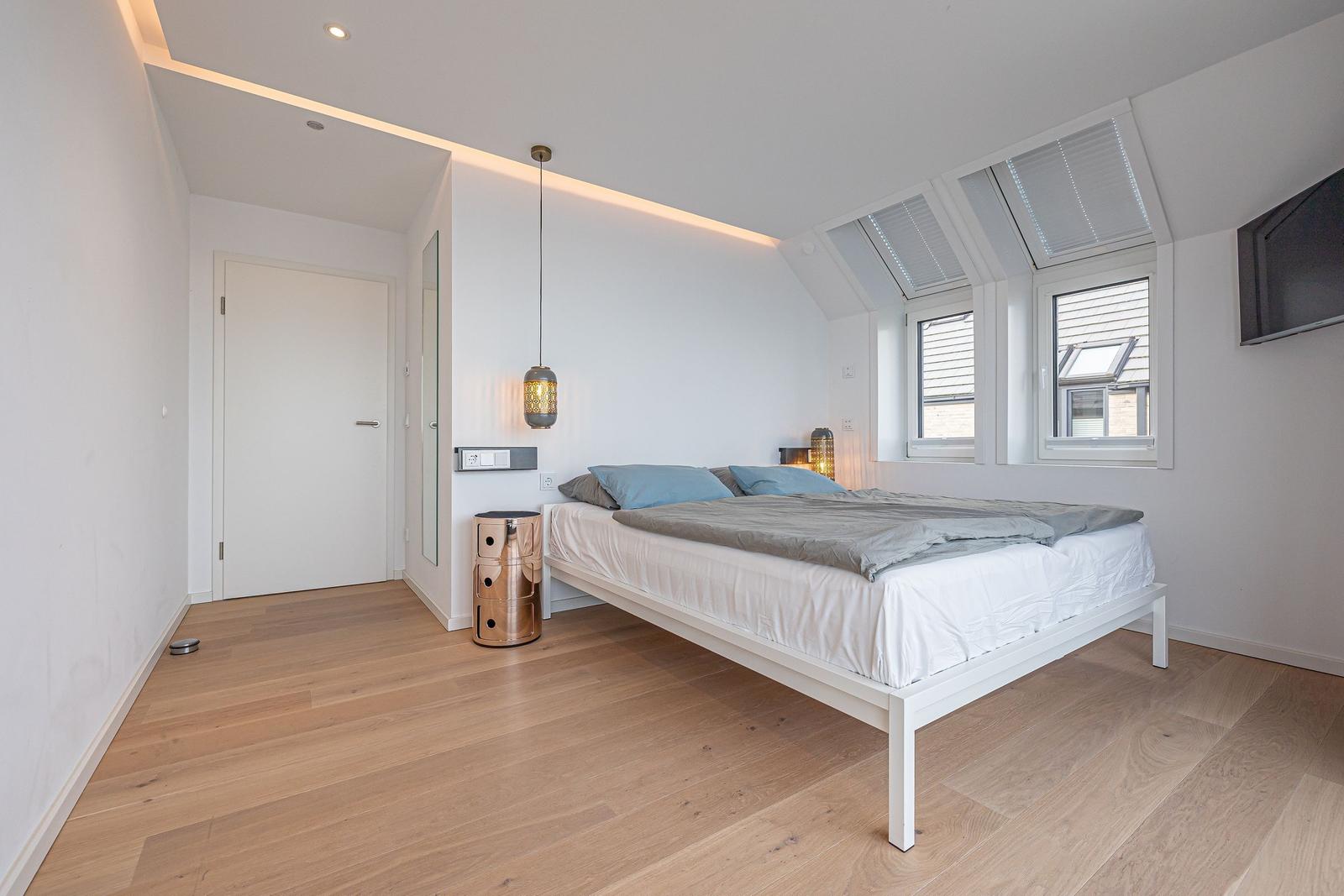 Schlafzimmer mit Dachschrägen, Fenstern und Bett.