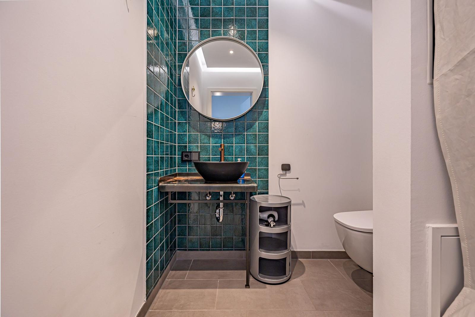 Badezimmer mit blauen Fliesen, runden Spiegel und Waschbecken