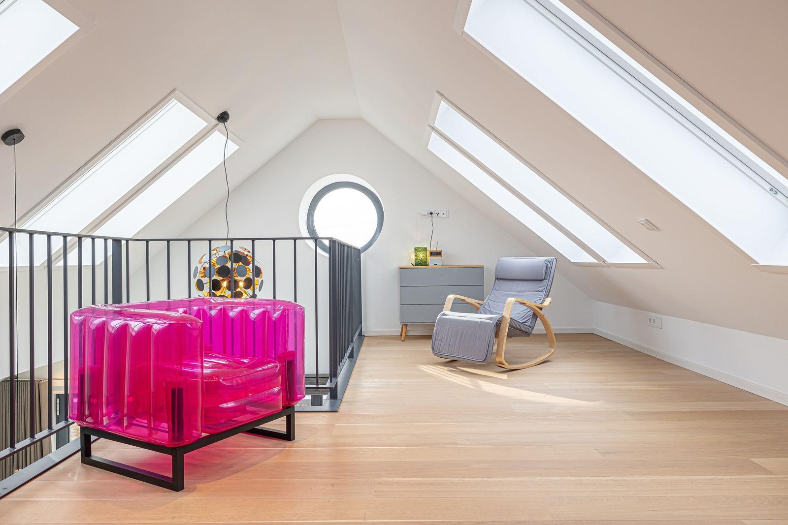 Dachgeschosszimmer mit pinkem Sessel, Sitzgelegenheit und Holzboden.