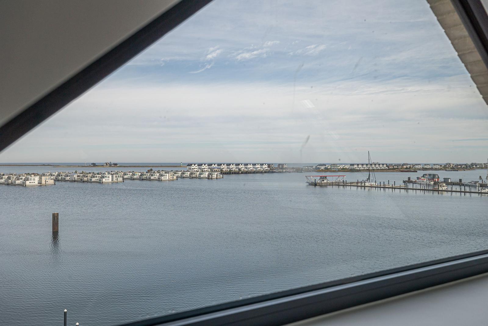 Aus dem Fenster sieht man Wasser, Boote und Ferienhäuser am Ufer.