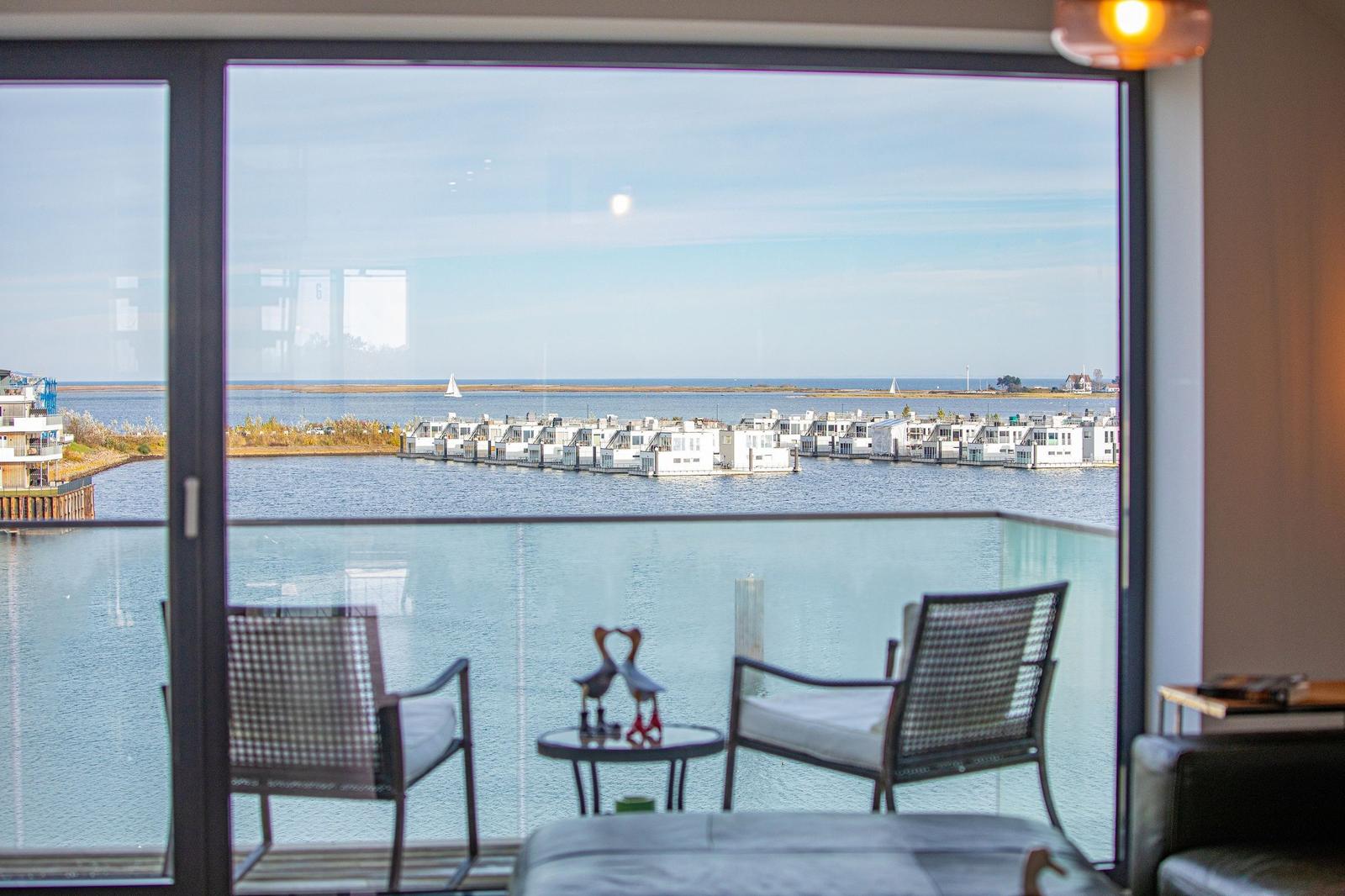 Balkon mit Sitzgelegenheiten und Blick auf Wasser und Häuser.