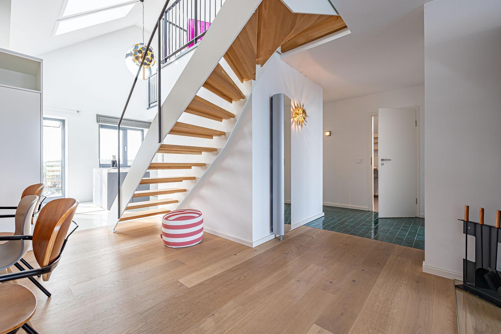 Eingangsbereich mit Holztreppe, Sitzkissen und moderner Beleuchtung.