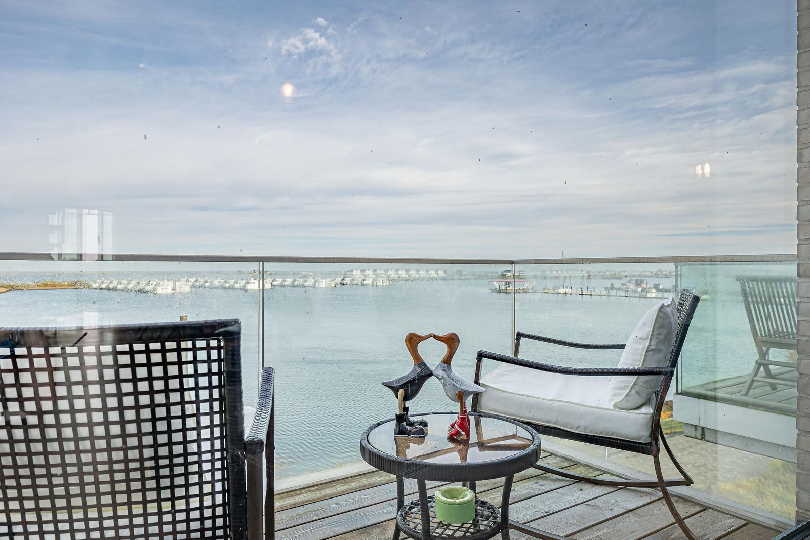 Terrasse mit Sitzgelegenheiten und Blick auf Wasser und Ferienhäuser.