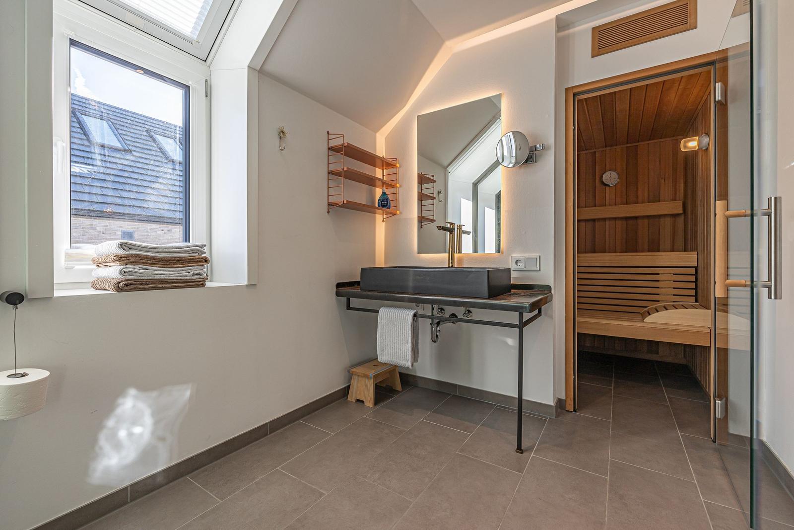 Badezimmer mit Sauna, Waschtisch und Fenster