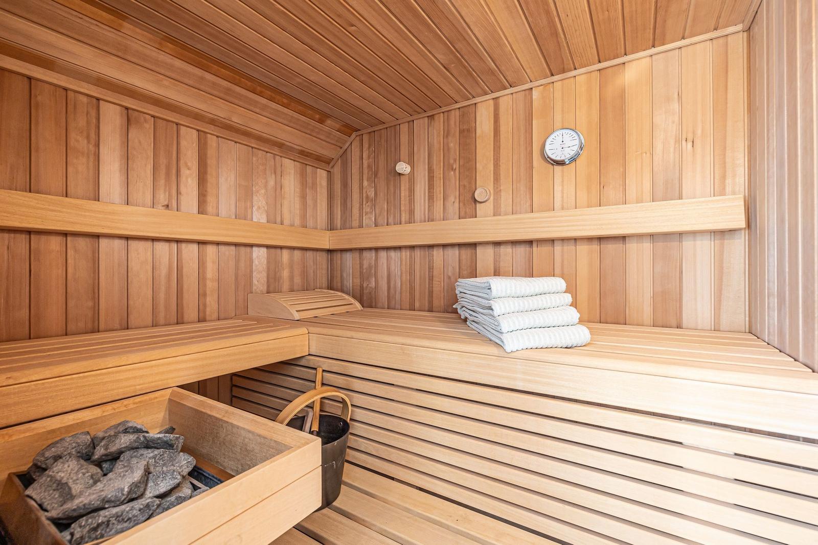Sauna mit Holzbank, gefalteten Handtüchern und Steinbehälter.