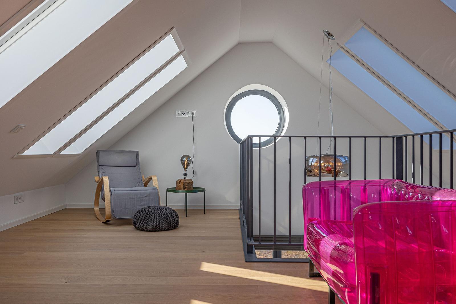 Dachgeschosszimmer mit Sitzgelegenheit und runden Fenster