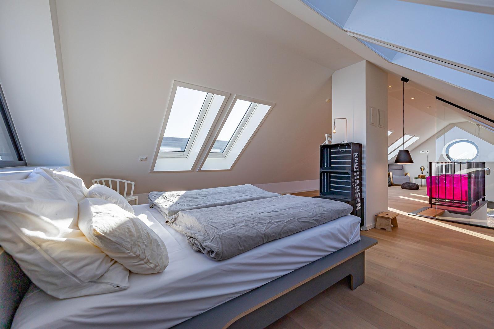 Schlafzimmer mit Dachfenstern und Blick in Wohnbereich