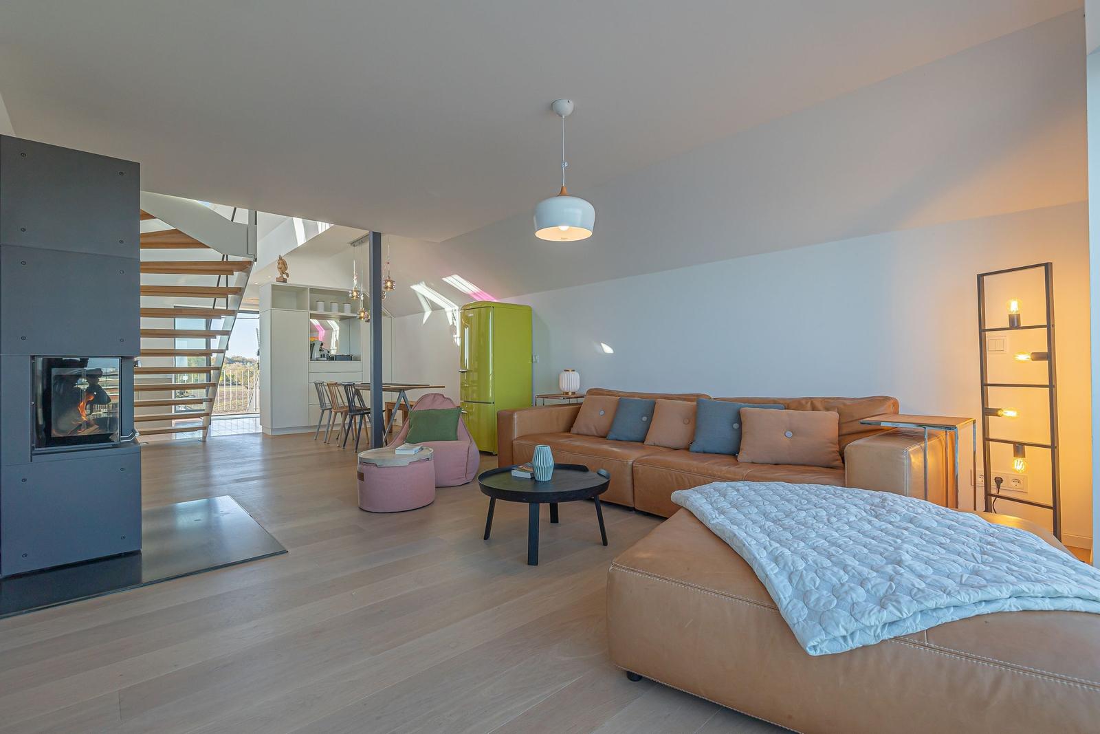 Wohnbereich mit Sofa, Kamin und Blick in die Küche.