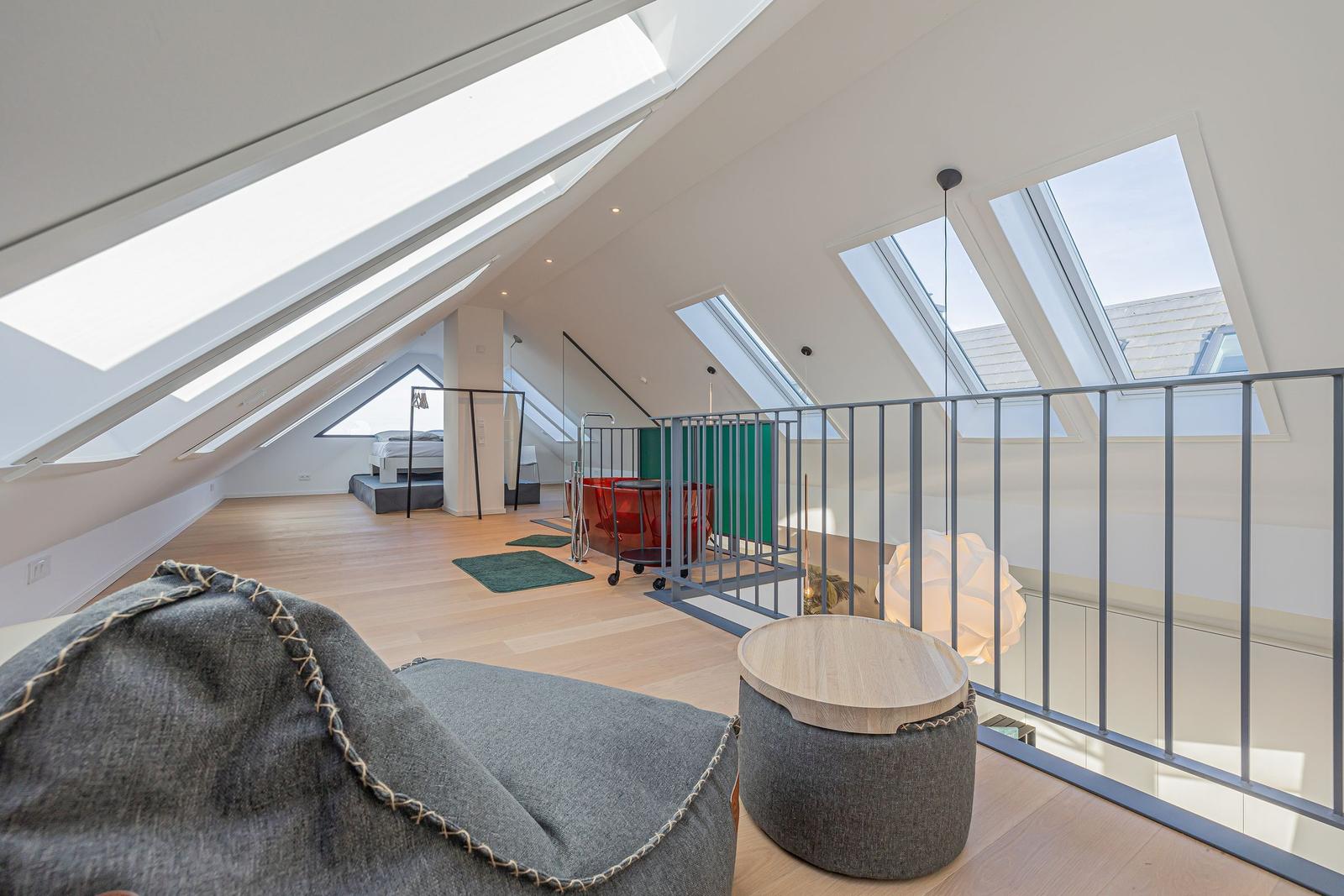Dachgeschoss mit Dachfenstern, Bett, Badezimmer und Sitzgelegenheit.
