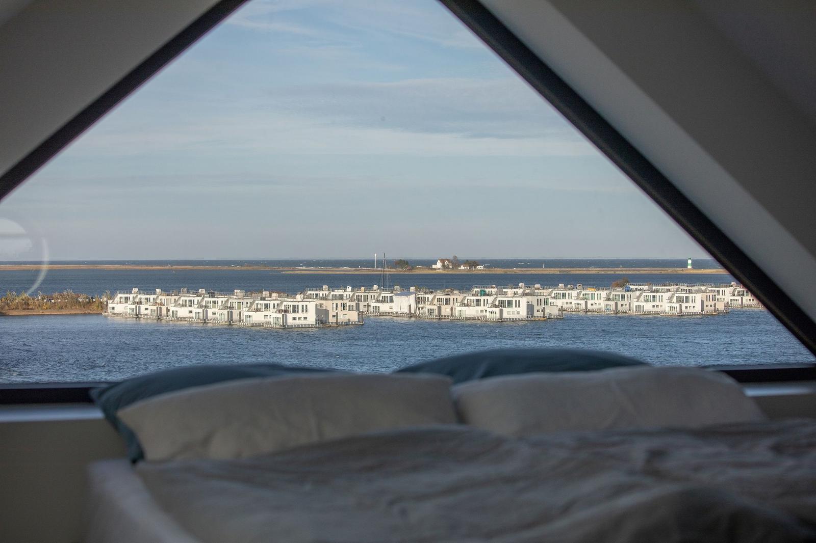 Aus dem Schlafzimmerfenster blickt man auf Wasser und Hausbootanlagen.