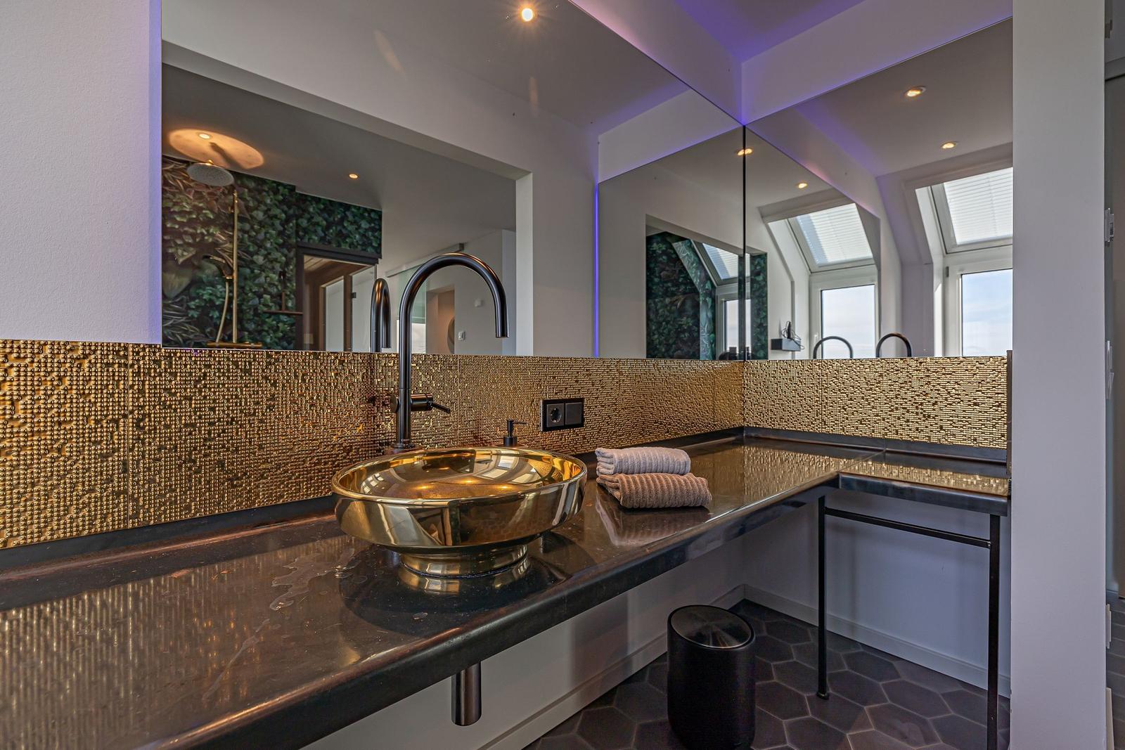 Bad mit goldenem Waschbecken und Spiegelwand