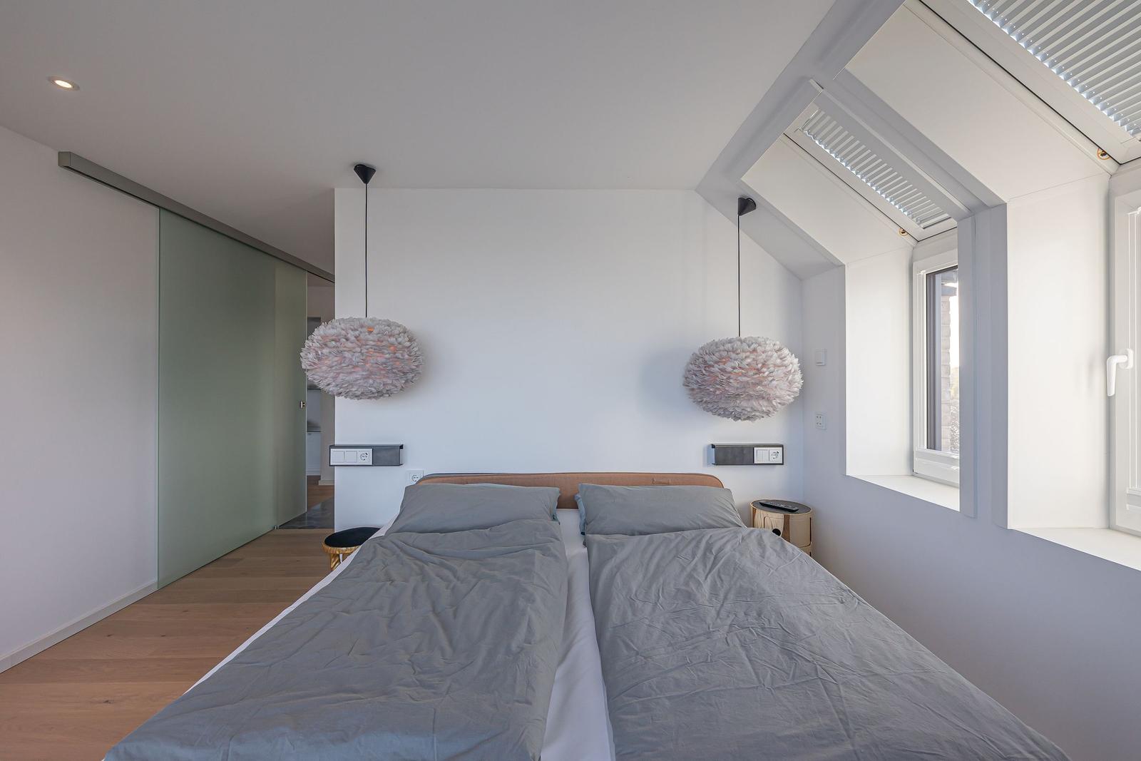Schlafzimmer mit Doppelbett, zwei hängenden Lampen und Schlupftür.