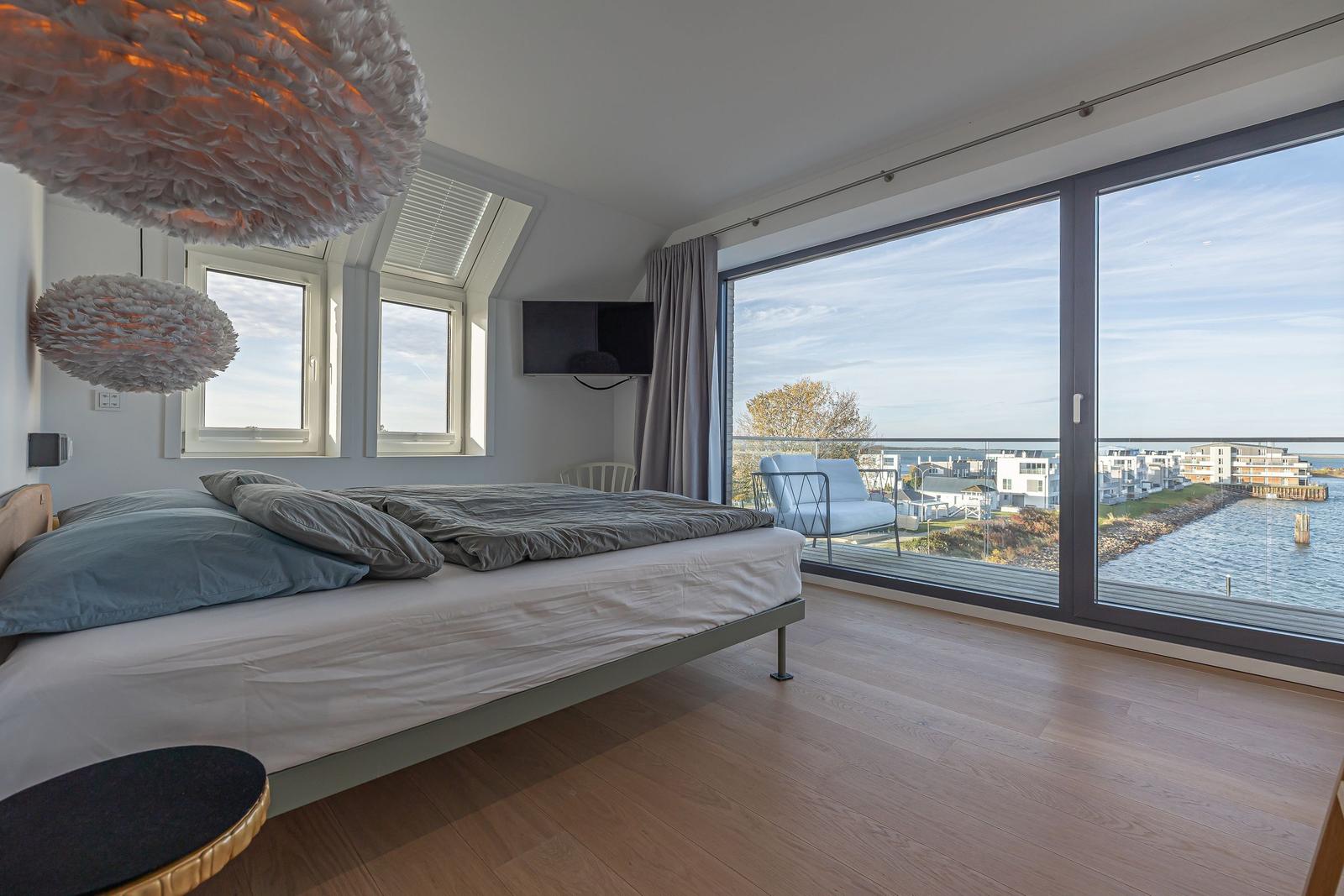 Schlafzimmer mit Balkonblick auf Wasser und Gebäude