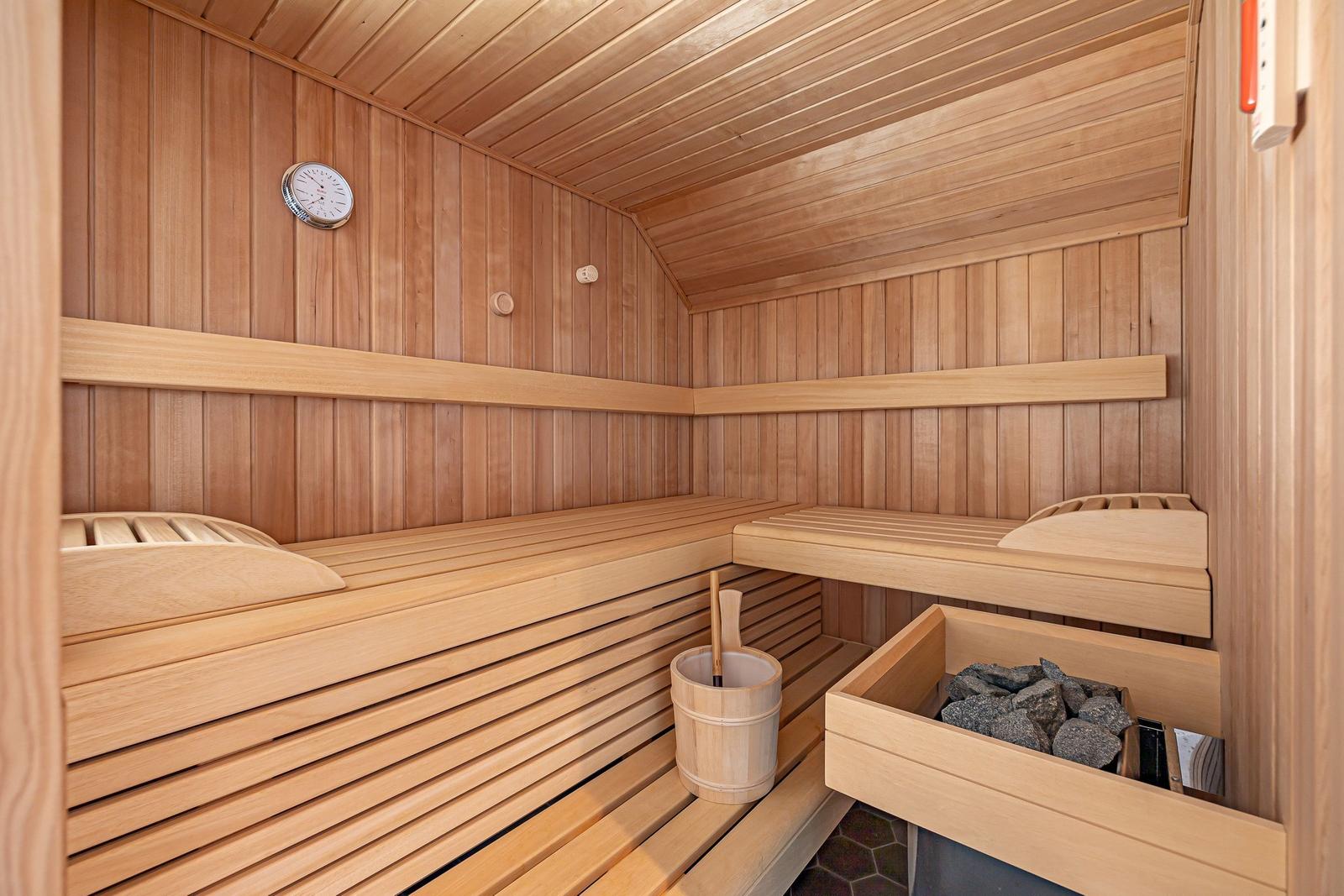 Sauna mit Holzbanken, Thermometer und Steinmulde.
