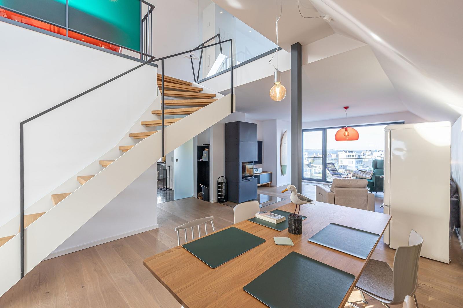 Essbereich mit Tisch, Stühlen und Tischdecken. Hintergrund zeigt Wohnbereich und Treppe.