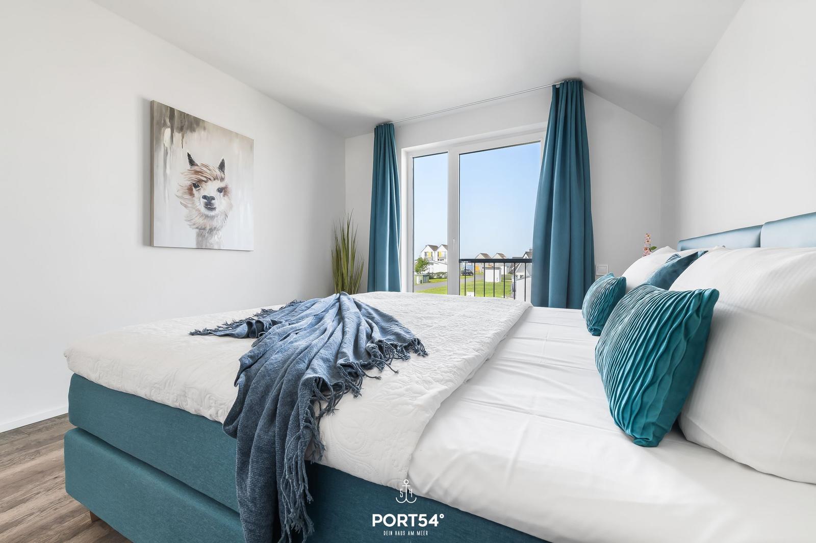 Schlafzimmer mit Bett, Fenster und Wandbild.