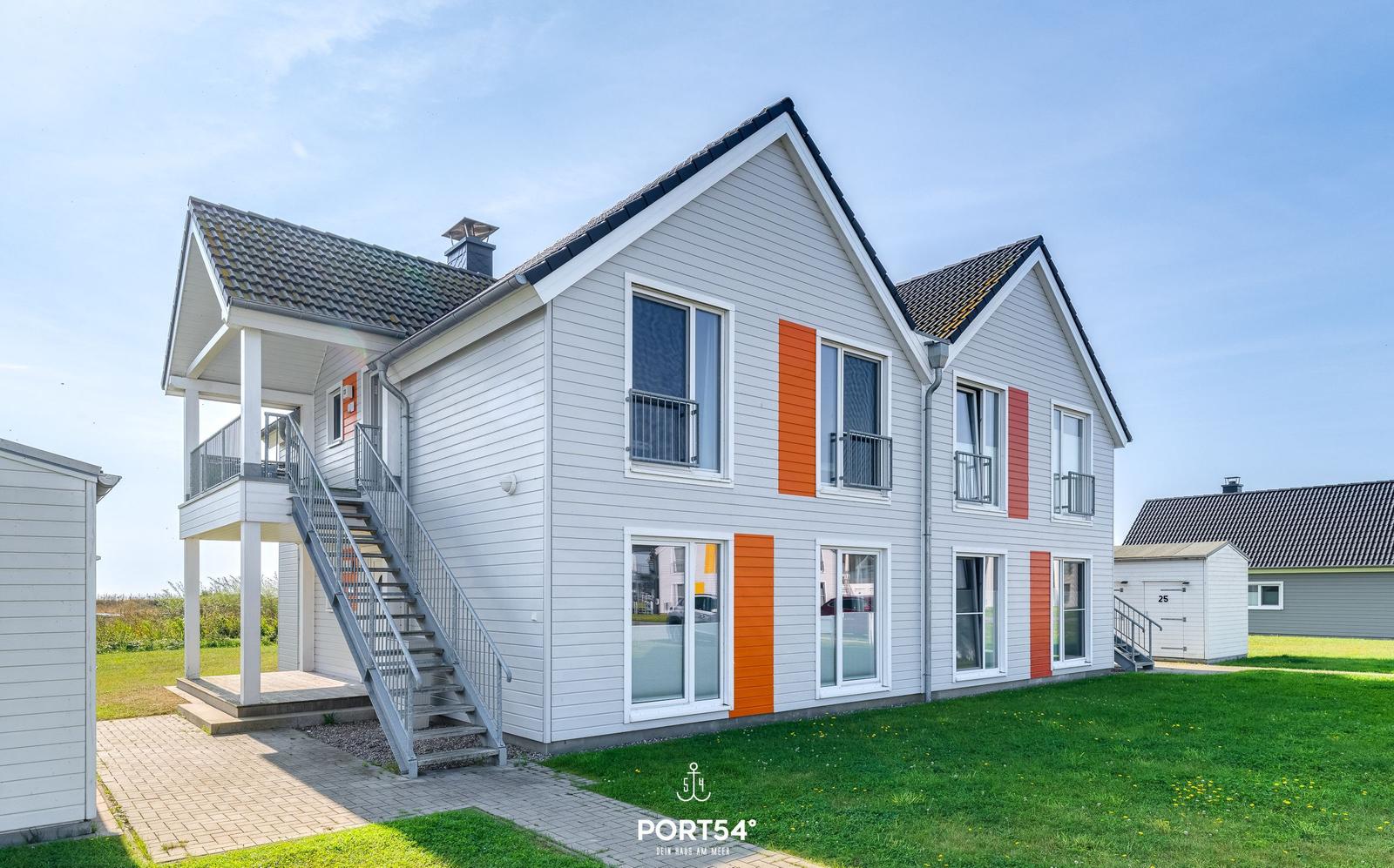 Zweistöckiges Haus mit orangefarbenen Akzenten und Balkonen.