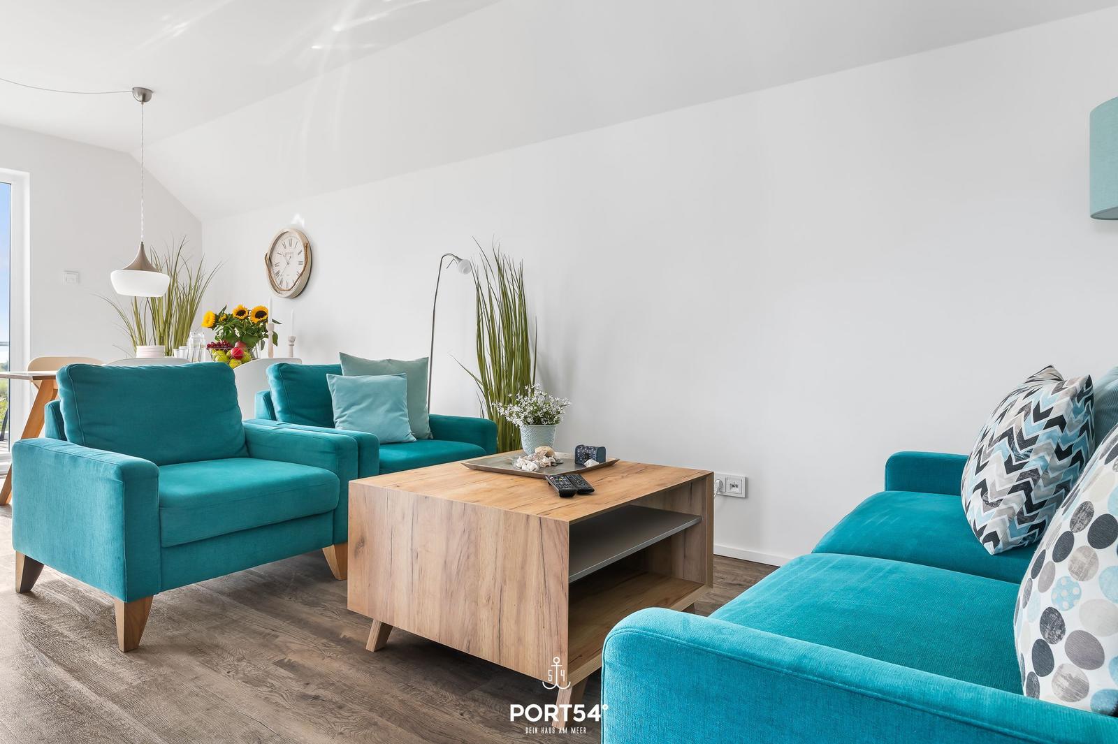 Wohnzimmer mit türkisfarbenen Sofas, Holz Couchtisch und Pflanzen.