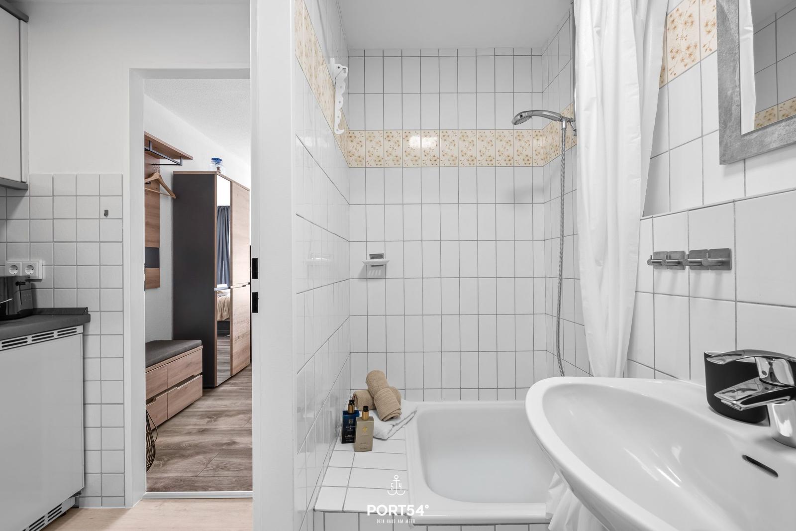Badezimmer mit Dusche, Waschbecken und Blick in Schlafzimmer