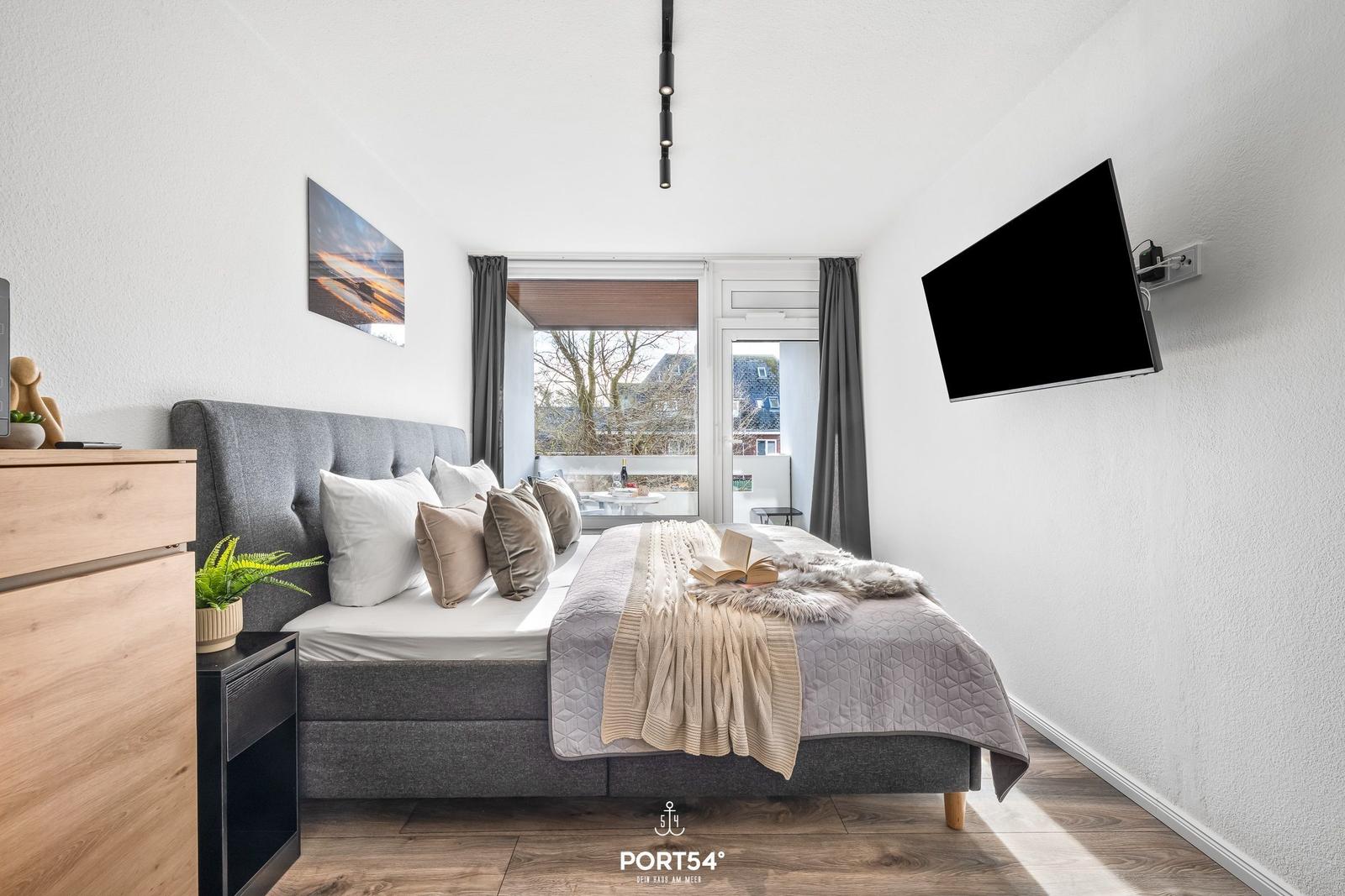 Schlafzimmer mit Bett, TV und Balkonansicht