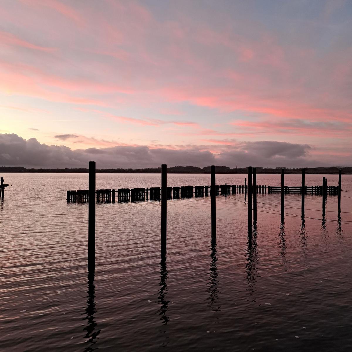 Sunset over water with posts and reflections
