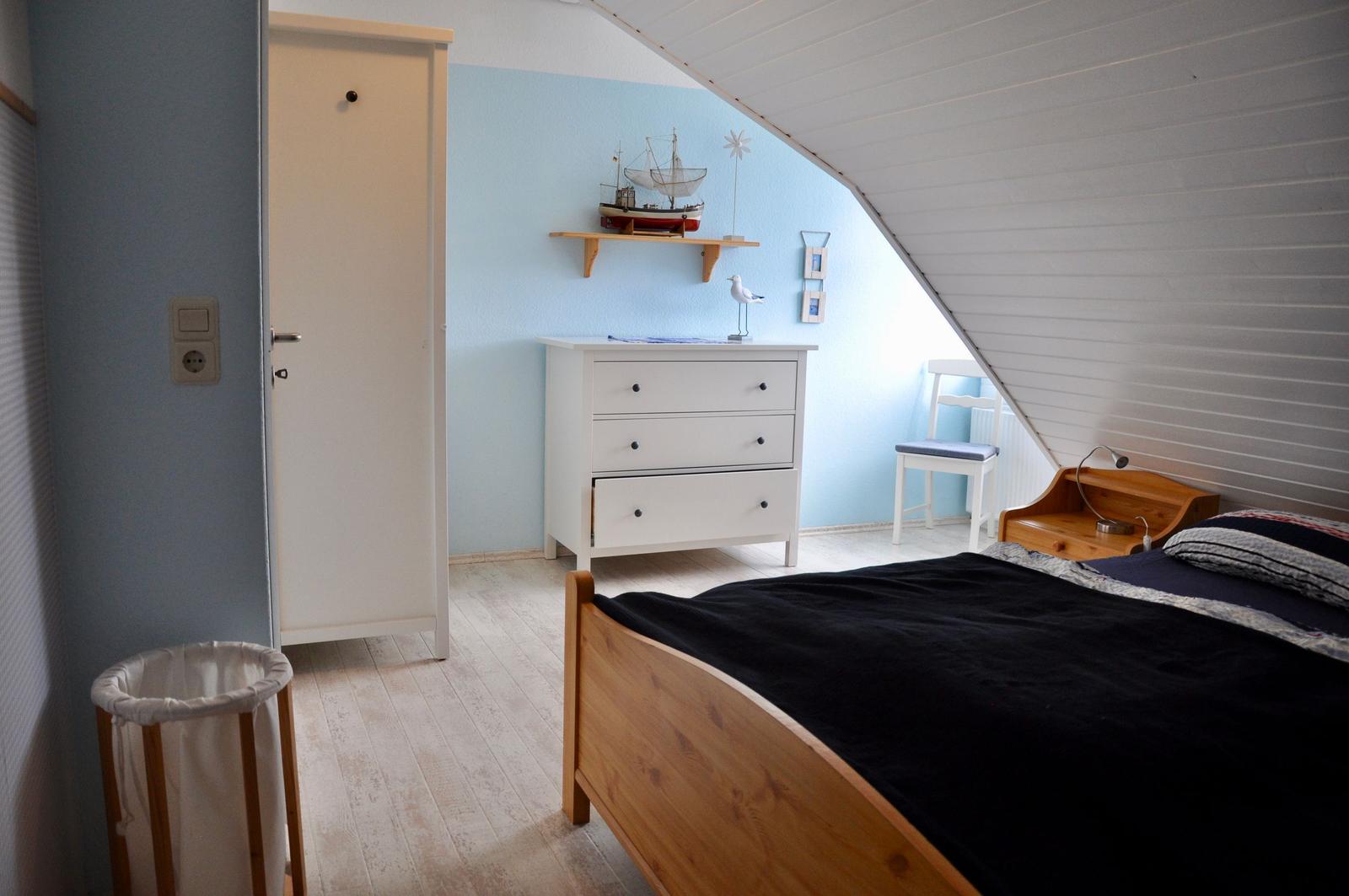 Schlafzimmer mit Dachschrägen, Bett, Schrank und Nachttisch.