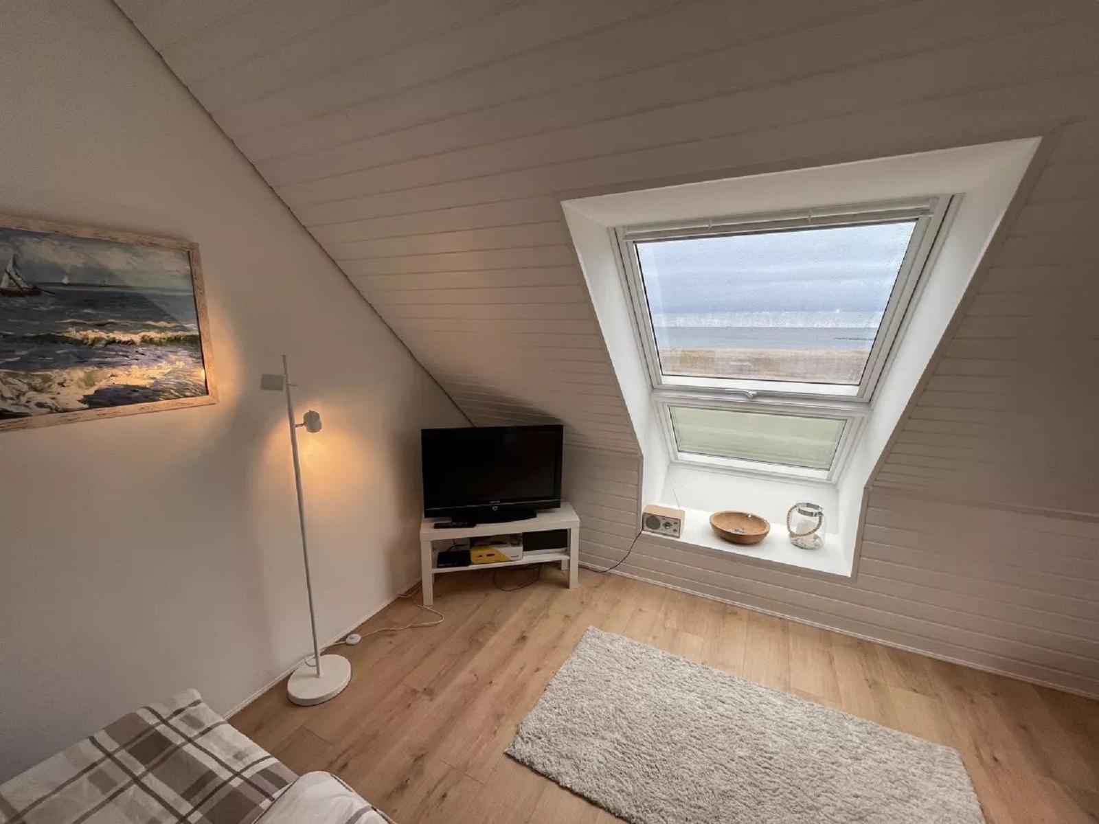 Kleines Zimmer mit Dachfenster, Fernseher und Wandbild an der Wand.