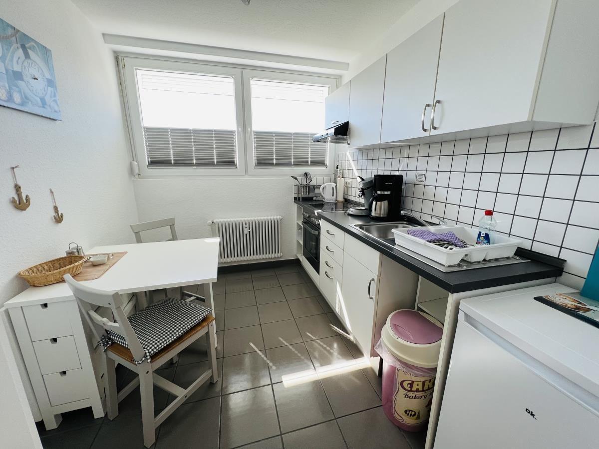 Kitchen with dining area, white cabinets, and windows with blinds.