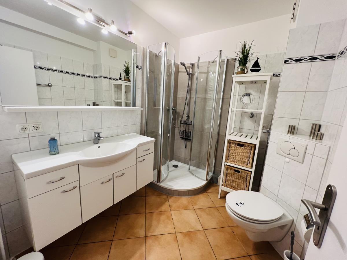 Bathroom with shower, sink and toilet. Tile floor and mirror cabinet.