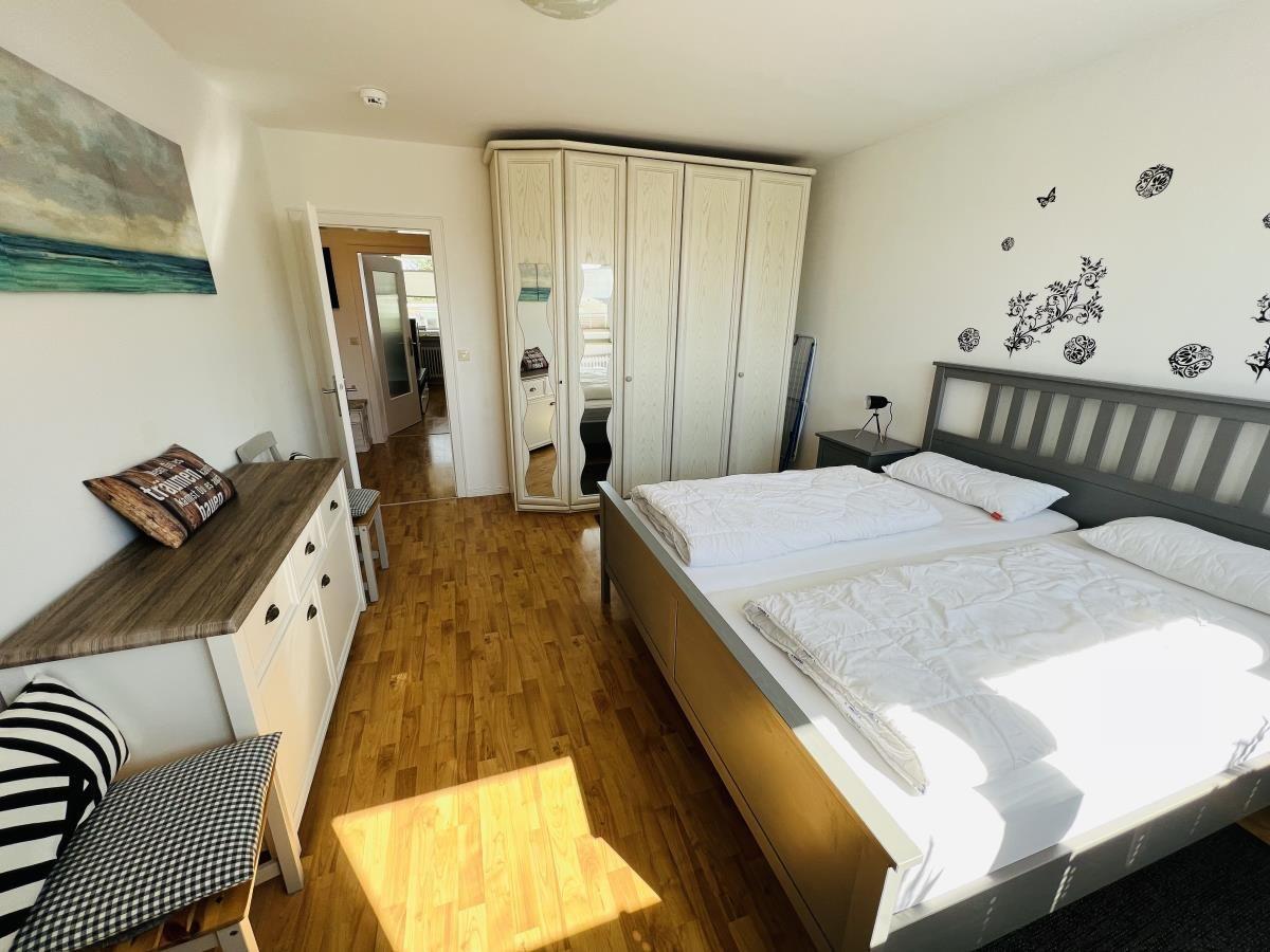 Bedroom with double bed, wardrobe, and hardwood floor.