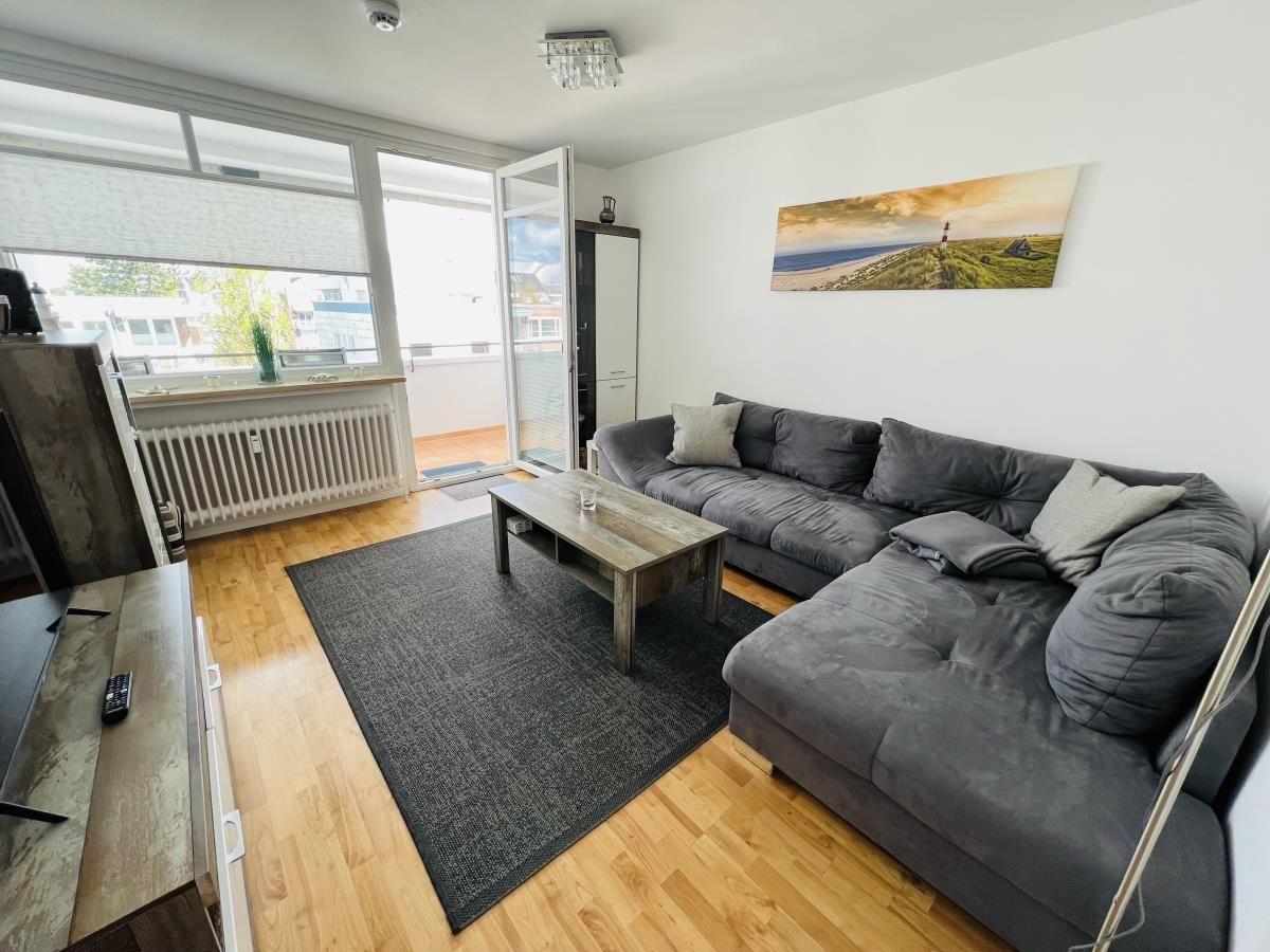 Living room with gray sofa, wooden floor, and balcony view.