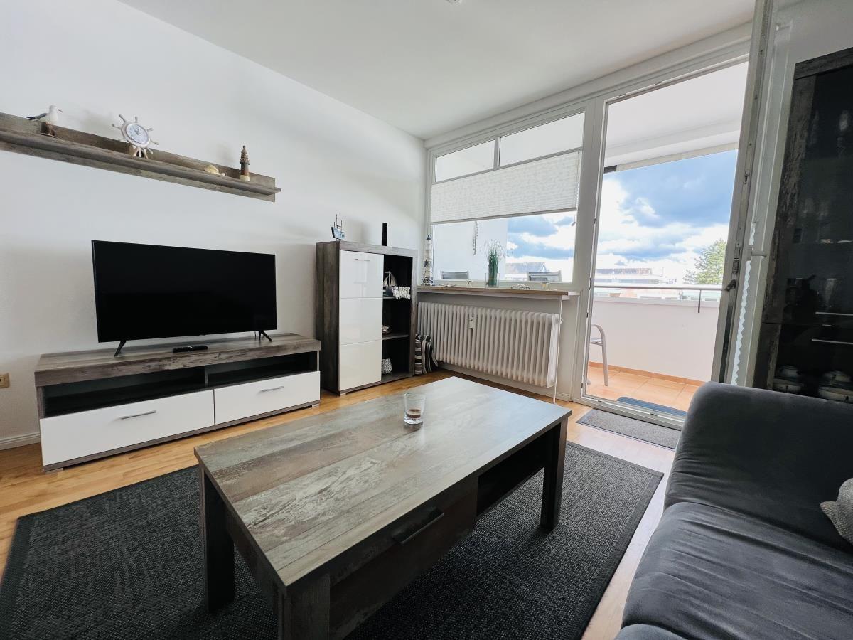 Living room with TV, sofa, and balcony access.