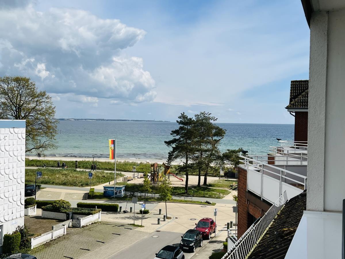 View of beach, park, and sea with playground and parking spots