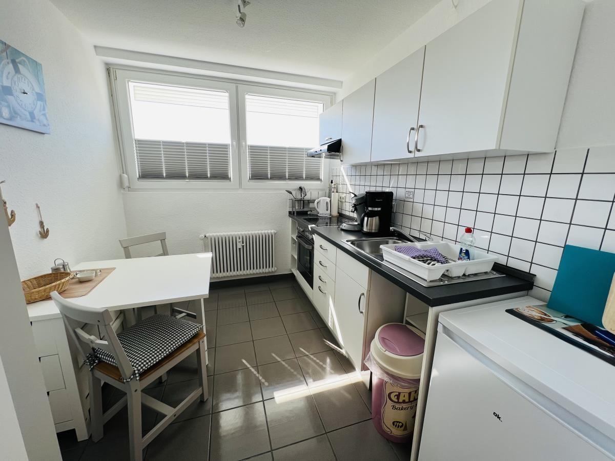 Kitchen with worktop, sink, refrigerator, and dining table with chairs.