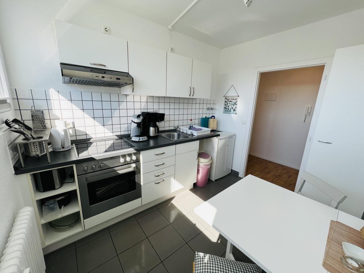 Kitchen with white cabinets, stove, and dining table