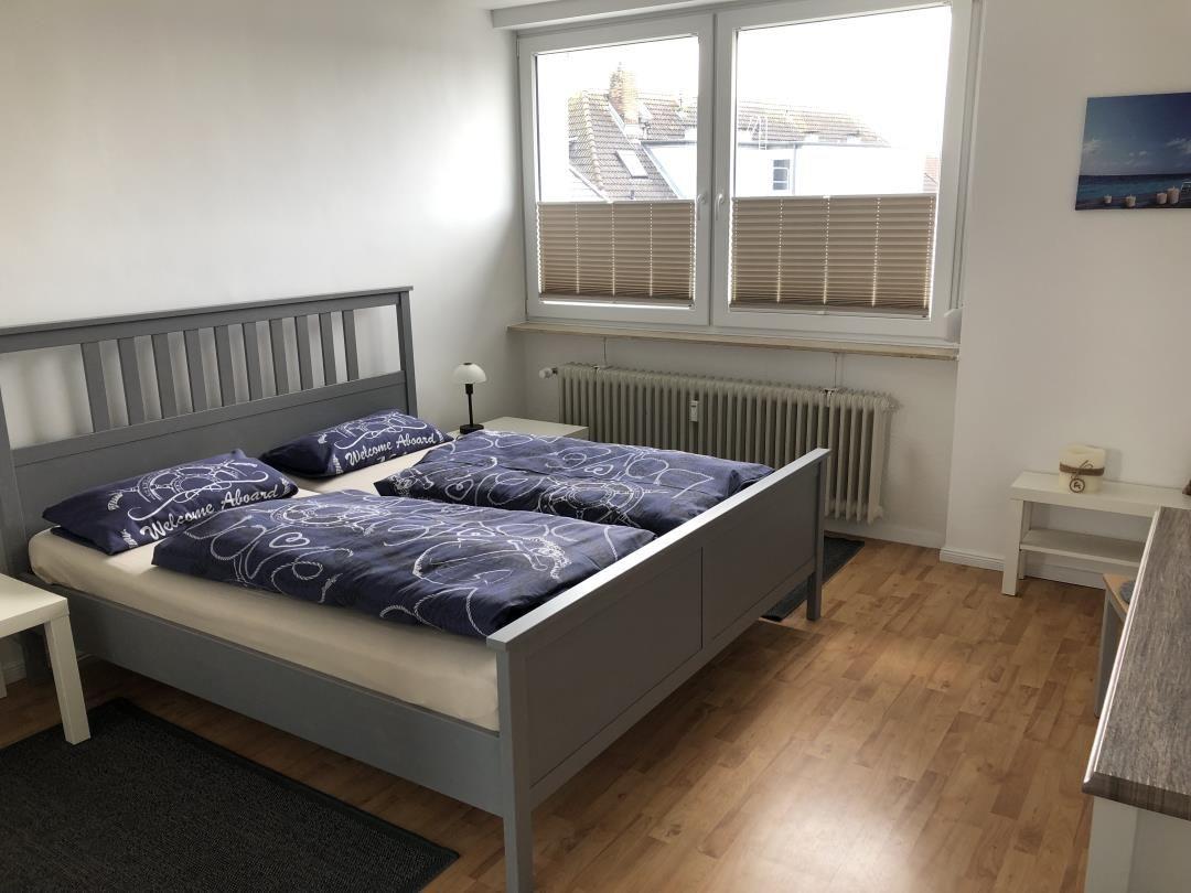 Bedroom with double bed, window, and wooden floor.