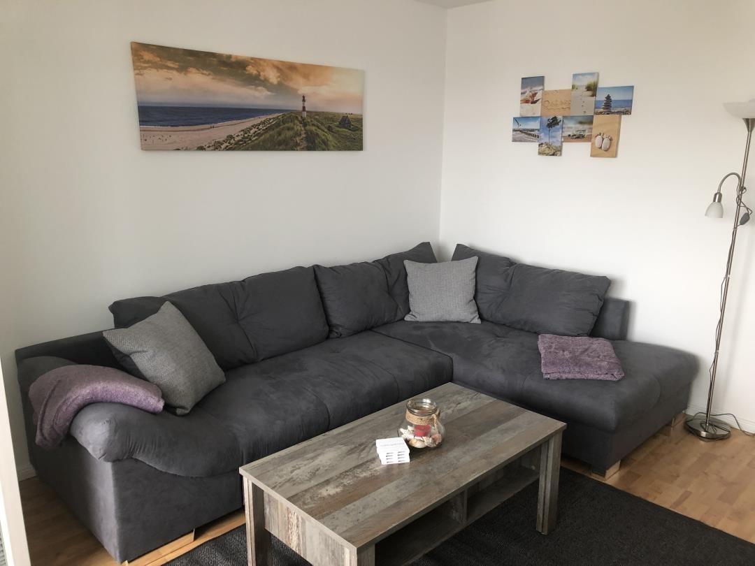 Living room with gray sofa, wooden table, and wall pictures.