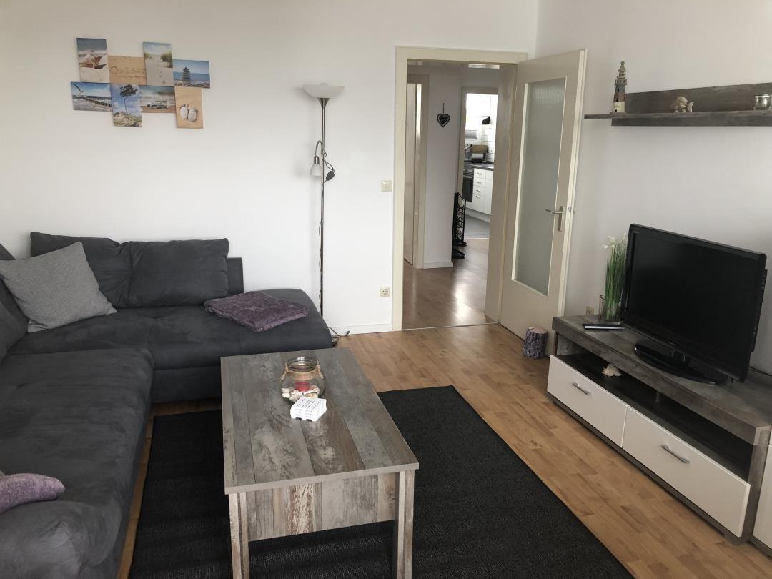 Living room with sofa, coffee table, and TV. Passage to the kitchen.