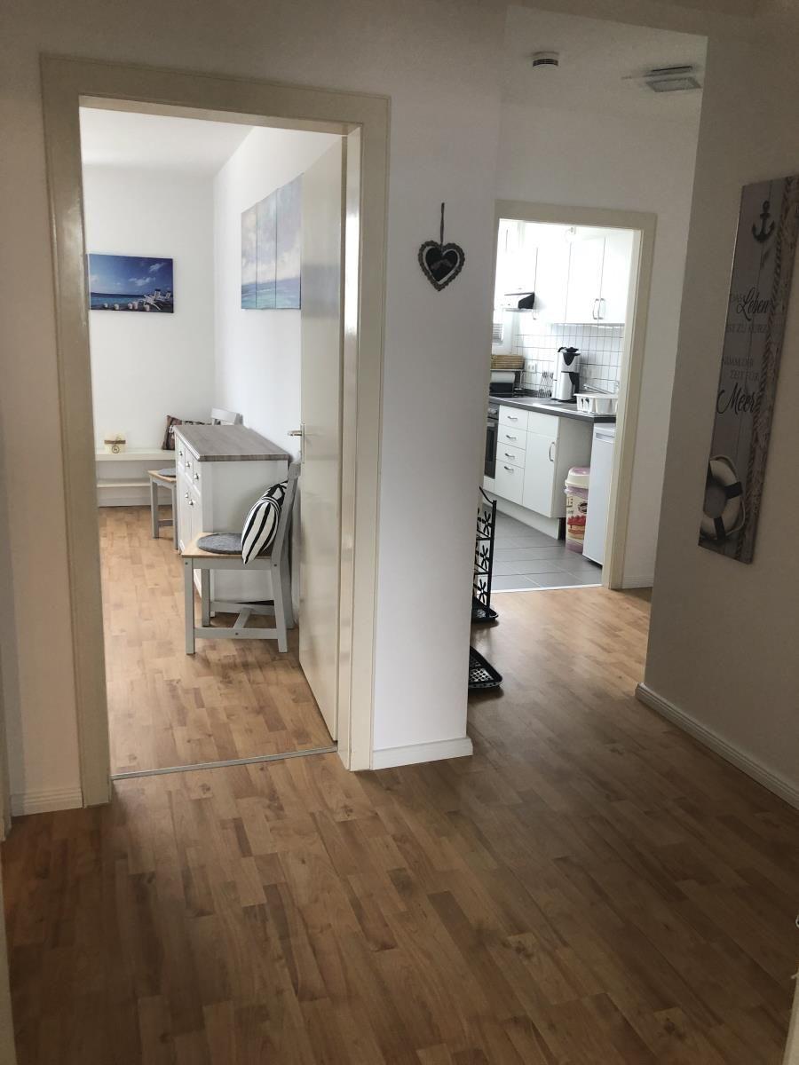 House with kitchen, dining area, and hallway with wooden floor and wall decor.