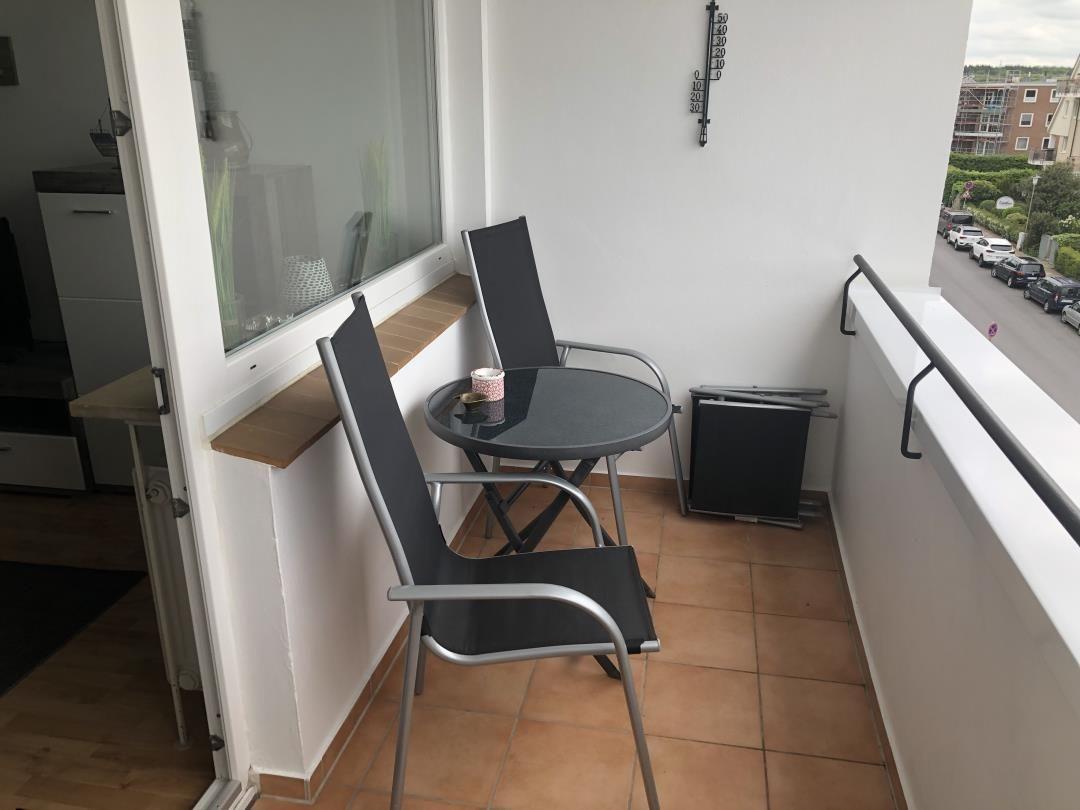 Balcony with table, two chairs, and view of street