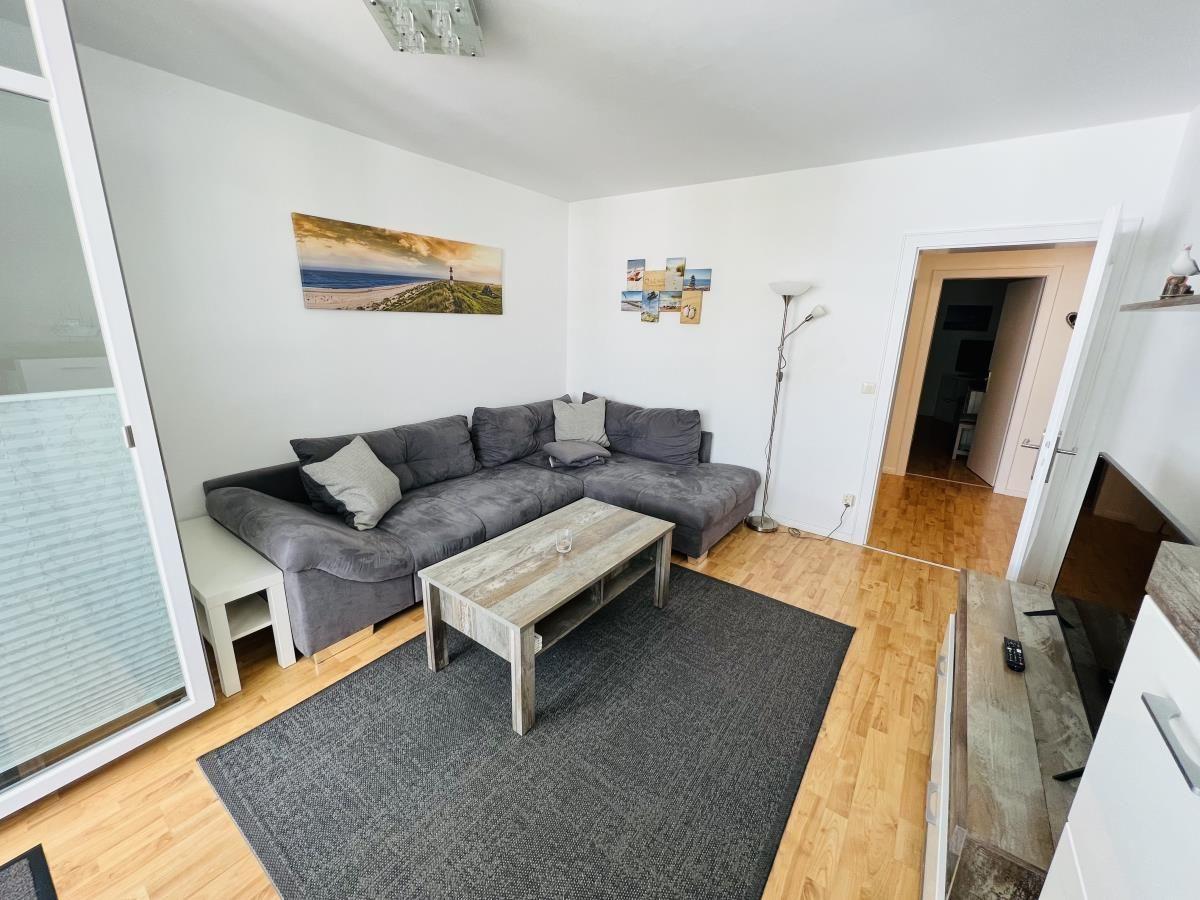 Living room with gray sofa, wooden floor, and wall pictures.