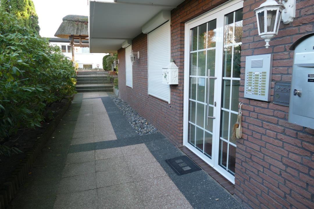 Eingangsbereich mit Glas-Tür, Briefkasten und Laterne an Backsteinwand.