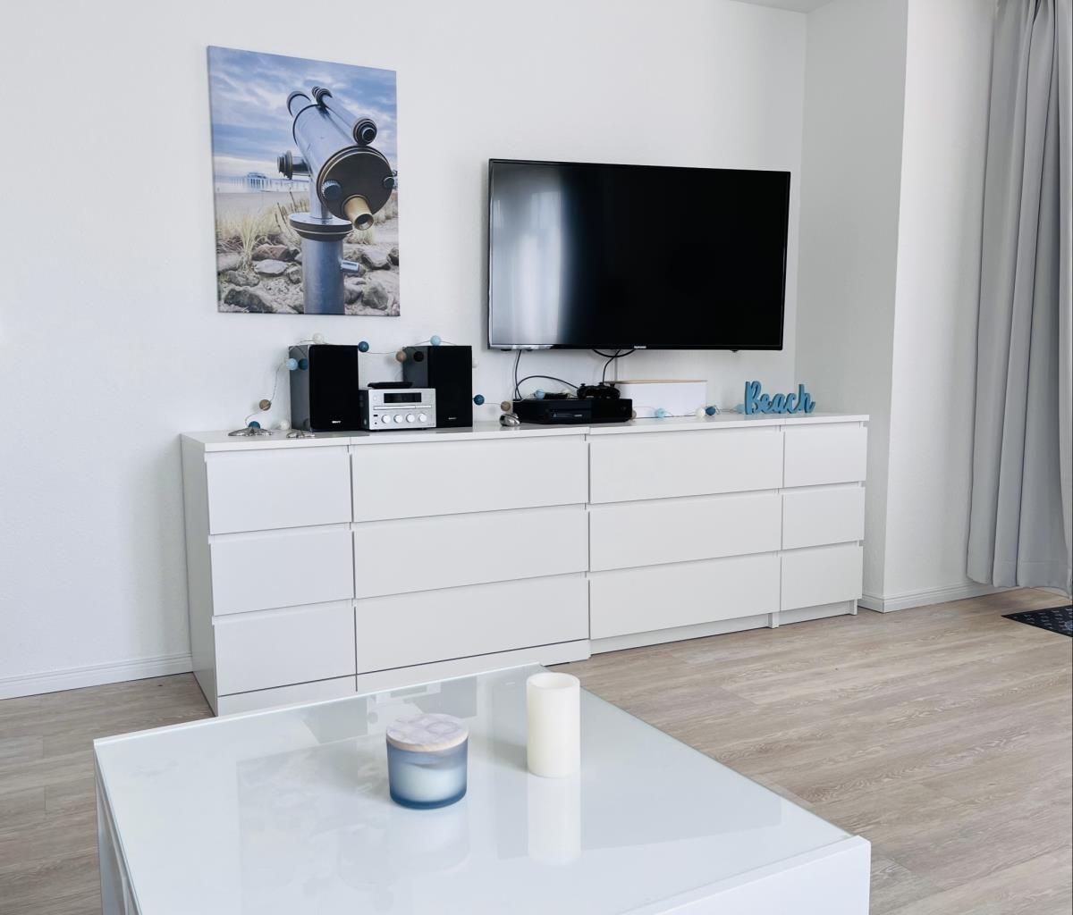 Living room with TV, white cabinets, and glass table.
