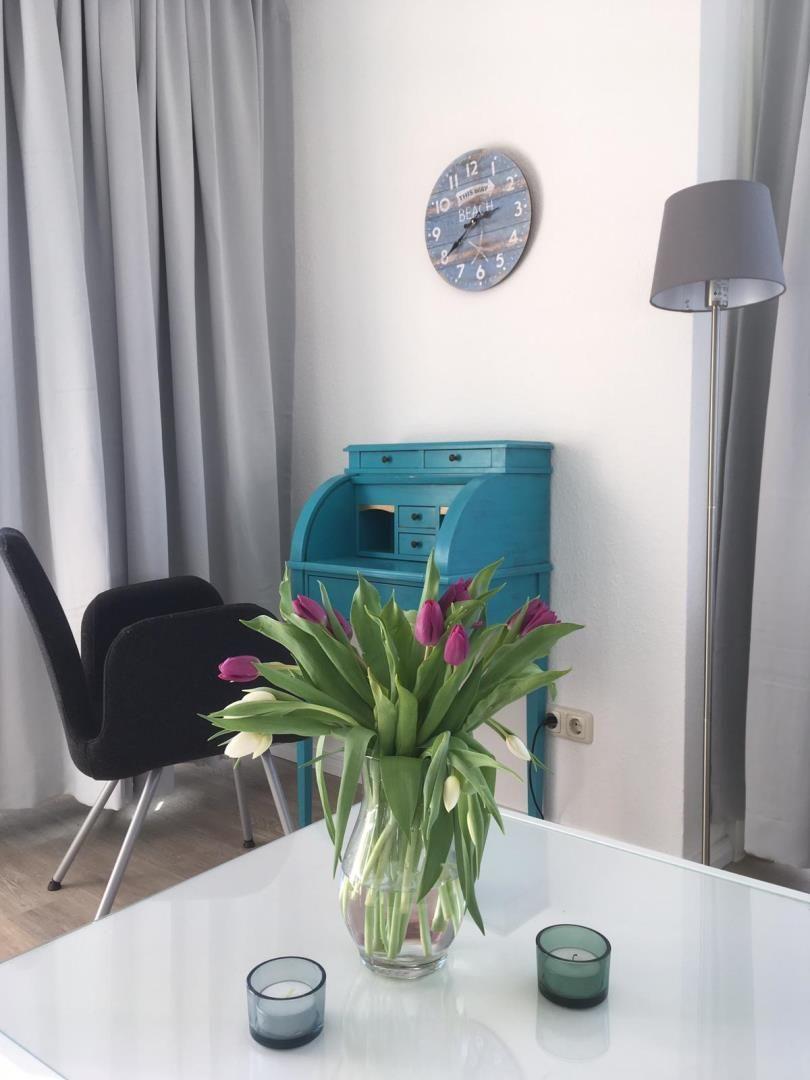 Table with tulips, blue desk, wall clock, and floor lamp